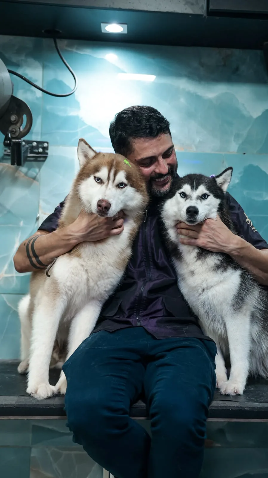 Vinícius Dei Gobbi sentado com dois huskies